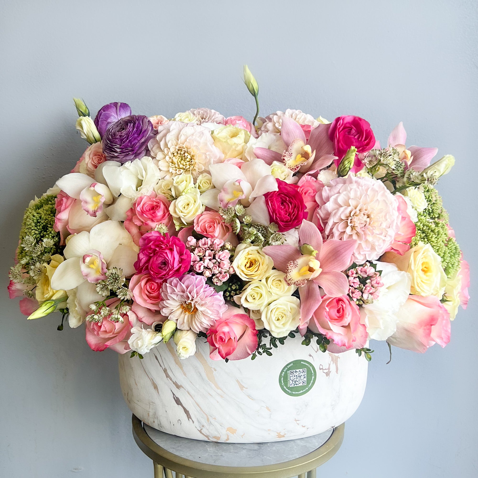 A large bouquet of colorful flowers arranged in a white vase, showcasing a vibrant display of nature's beauty