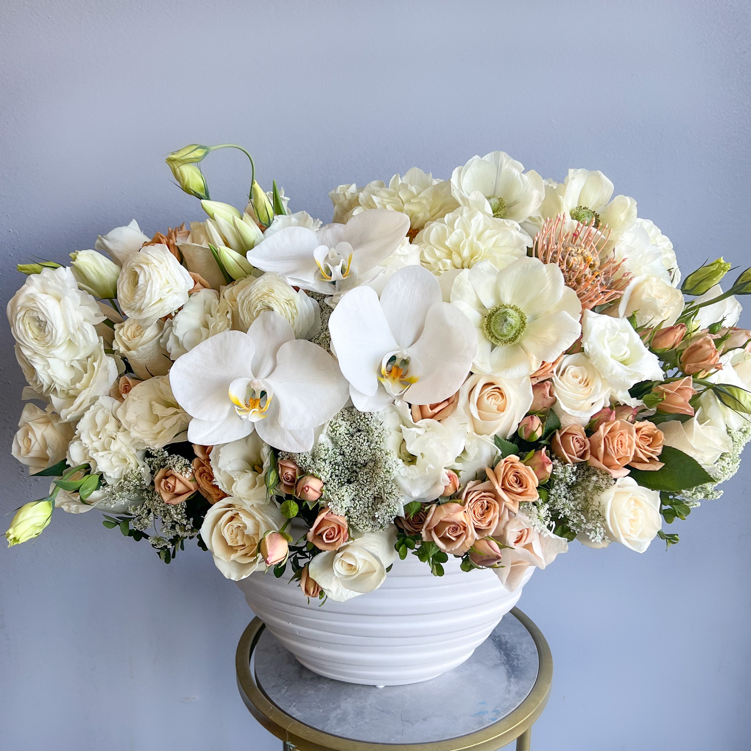 A white and peach floral arrangement in a white vase showcasing elegance