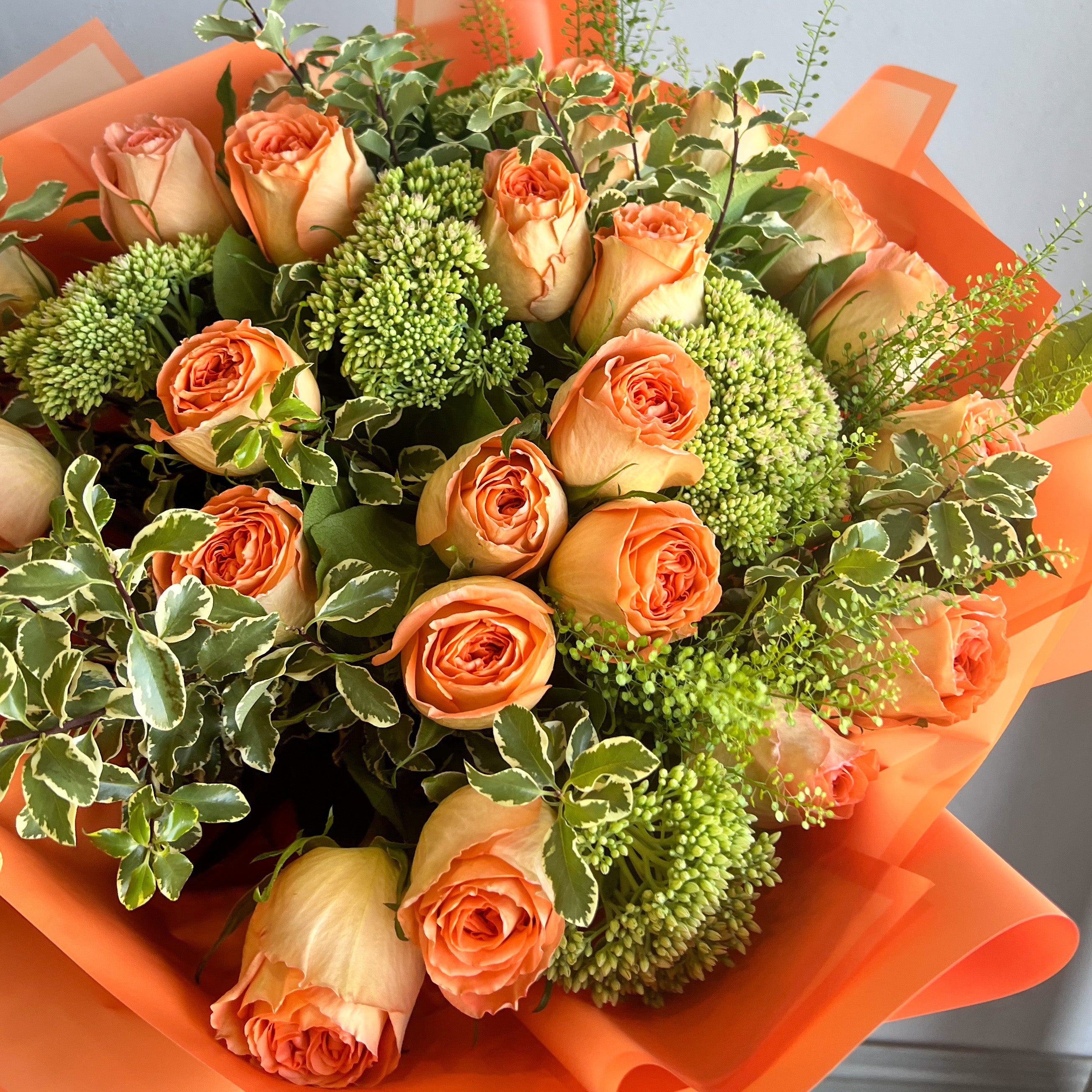 A delightful arrangement of orange roses in a wrapped flower bouquet, symbolizing warmth and joy.