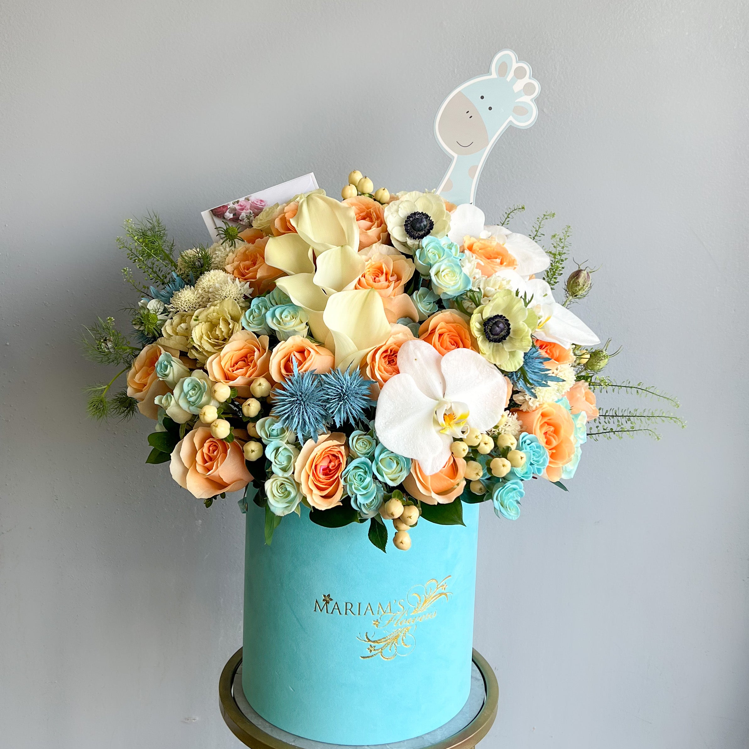 A blue floral box arrangement with a giraffe, capturing the essence of joy for a baby boy's gender reveal celebration.