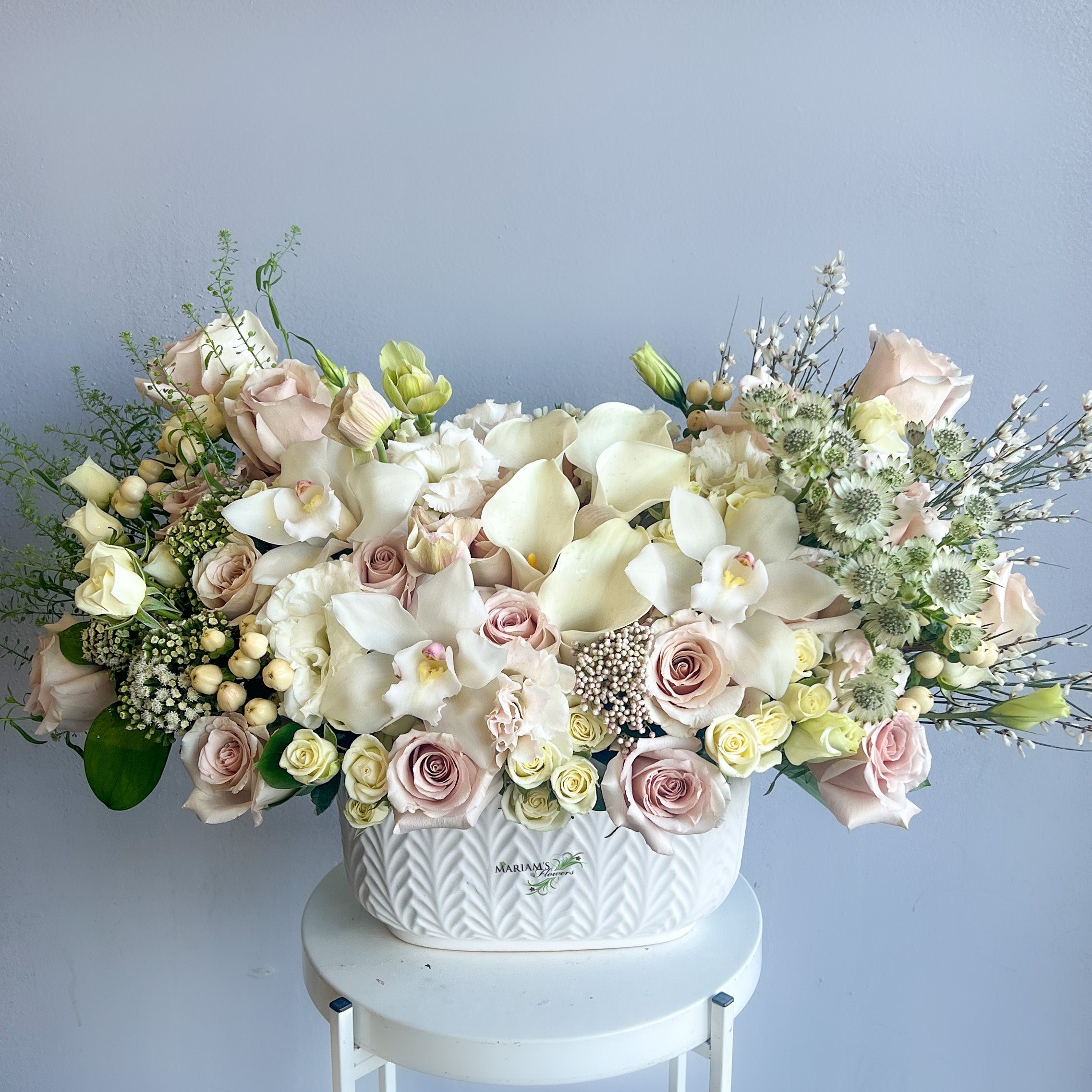 A white basket filled with pink and white flowers, showcasing a natural and elegant floral arrangement.