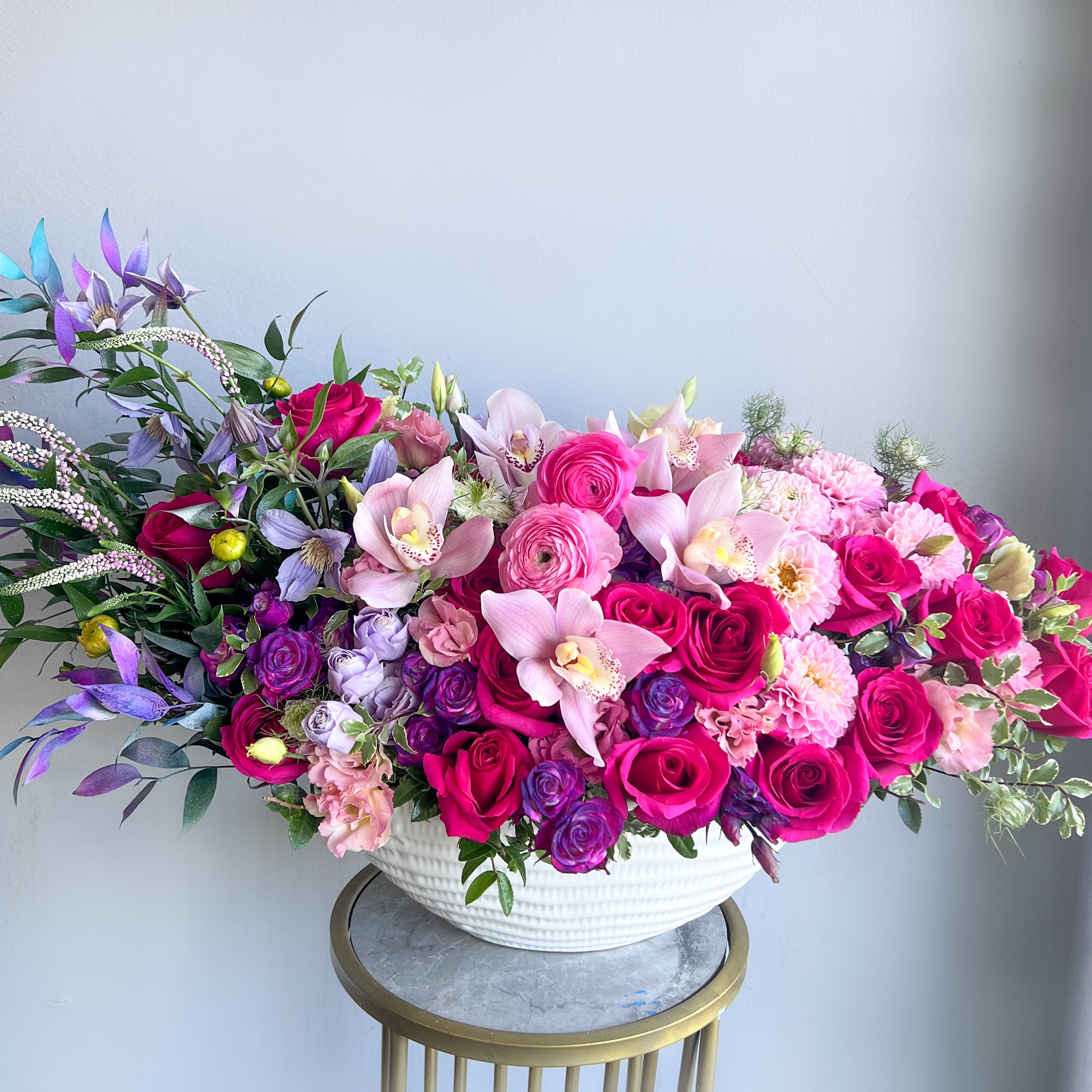 An exquisite display of pink and purple flowers in a vase, artistically arranged on a pedestal for a stunning visual impact